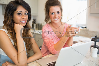 Two happy friends with laptop having coffee