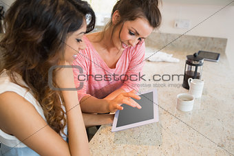 Smiling friends having coffee and using tablet computer