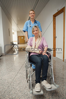 Nurse pushing wheelchair of patient with arm sling