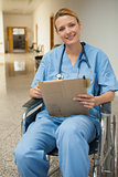 Smiling nurse checking her notes in a wheelchair