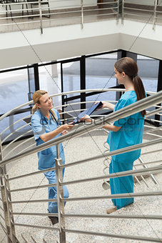 Nurse handing folder to other nurse