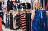 Woman holding up blue shirt in boutique
