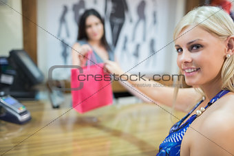 Woman taking purchases at cash register
