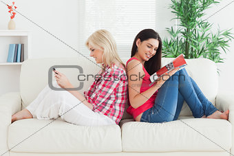 Women sitting back to back on the couch