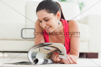 Woman lying on floor looking at magazine