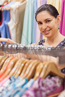 Woman standing by a clothes rack while smiling