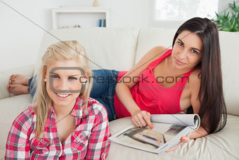 Woman looking at magazine on couch with friend