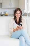 Smiling woman sitting on the couch and texting