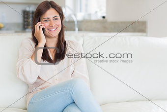 Woman phoning while sitting on the couch