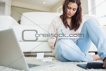 Woman sitting on the carpet and calculating bills