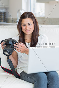 Brunette holding a camera and a laptop