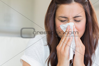 Brunette blowing nose into tissue