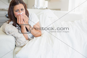 Woman with a cold lying on sofa