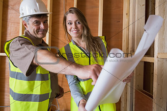 Two architects smiling with blueprints