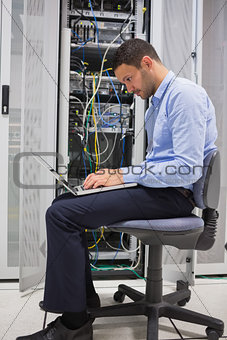 Man on his laptop beside servers