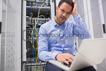 Technician getting frustrated with laptop over servers