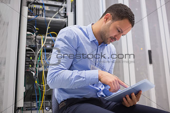 Man using tablet pc beside servers
