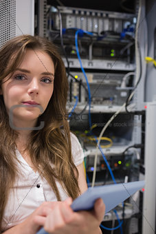 Woman with tablet pc standing in front of servers