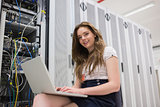 Smiling woman with laptop working with servers