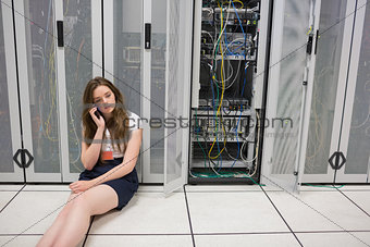 Woman sitting on the floor beside servers on the phone