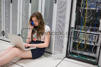 Woman checking the servers with laptop and talking on phone