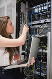 Woman adjusting server wires and holding laptop