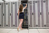 Woman standing in the hallway and fixing wires in data center