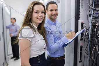 Two smiling technicians checking the servers