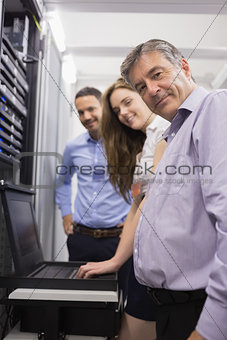 Three happy technicians checking servers with laptop