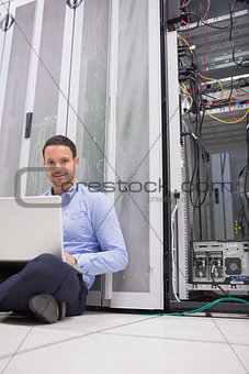 Man sitting on floor using laptop to check servers