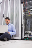 Man working with his laptop on the floor beside servers