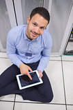 Smiling man using tablet pc beside servers