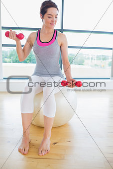 Woman lifting weights on exercise ball