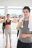 Man standing at the gym holding a bottle of water