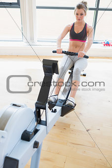 Woman sitting at the row machine pulling