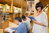 Smiling woman holding a tablet pc in the library