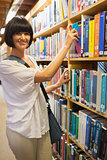 Black-haired woman taking a book out of the shelves