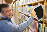 Smiling man taking a tablet pc from shelves