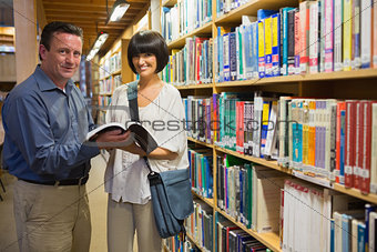 Man showing woman book in library