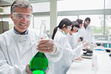 Smiling chemist raising a liquid