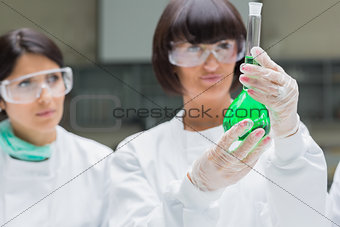 Female chemists viewing green liquid
