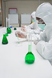 Chemists in protective suits working with green chemical