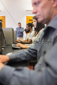 Teacher standing and smiling in computer class