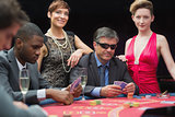 Man in sunglasses playing poker with two women either side