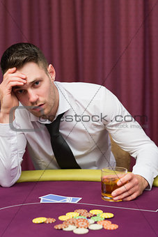 Man drinking whiskey at poker table