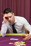 Man leaning on poker table holding cigar