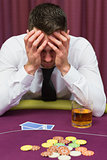 Man leaning on poker table looking worried