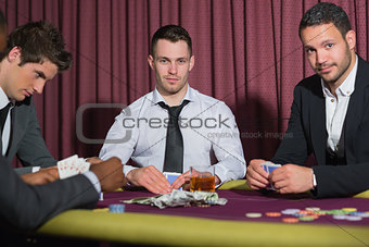Two smiling men looking up from poker game