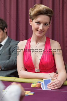 Woman sitting at the table holding cards smiling
