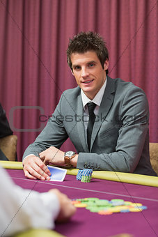 Man sitting at the table smiling while holding cards